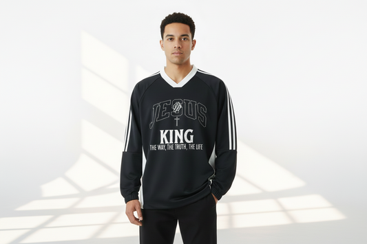 Man wearing a black long-sleeve shirt with 'Jesus King' text on a white background