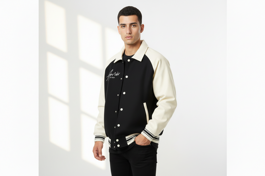 Man wearing a black and white varsity jacket with a brand logo on a white background